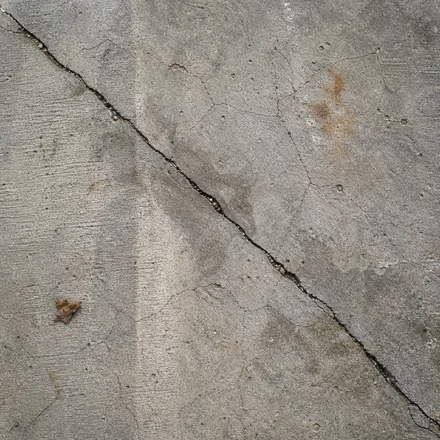Old grey concrete pool deck with hairline cracks
